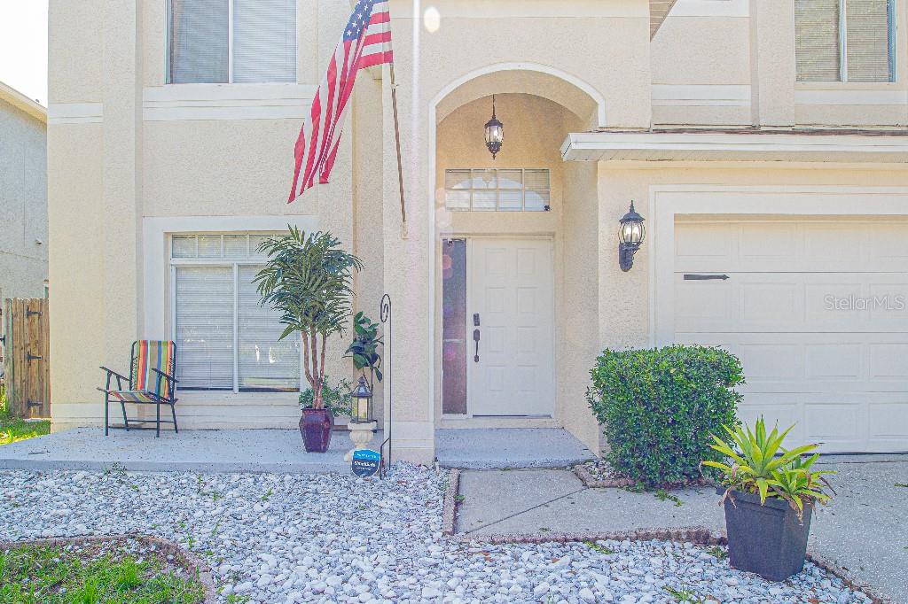 The exterior of a two-story home features a white front door, garage, and gravel landscaping — 1745 OAK POND COURT, OLDSMAR, FL