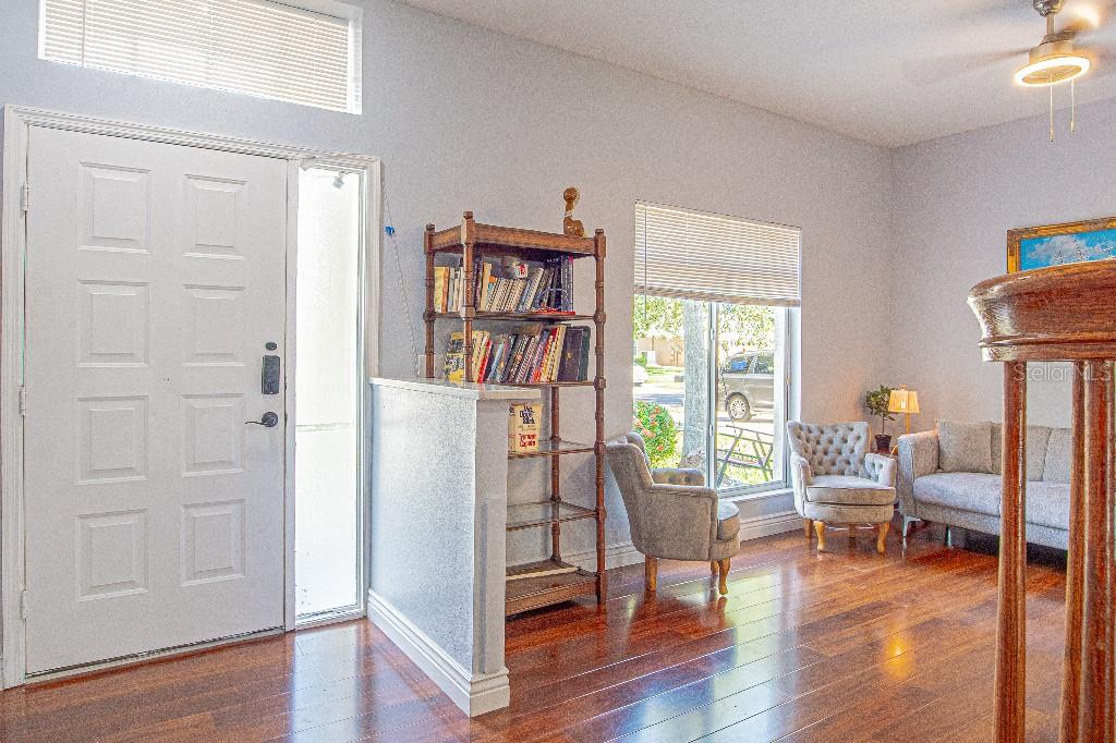 A living room features hardwood floors, a bookshelf, a front door, and seating furniture — 1745 OAK POND COURT, OLDSMAR, FL