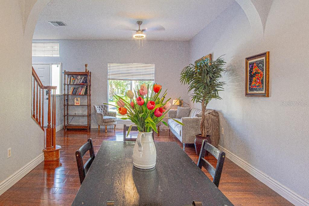 A dining area with a dark table, hardwood floors, and an adjacent living space — 1745 OAK POND COURT, OLDSMAR, FL