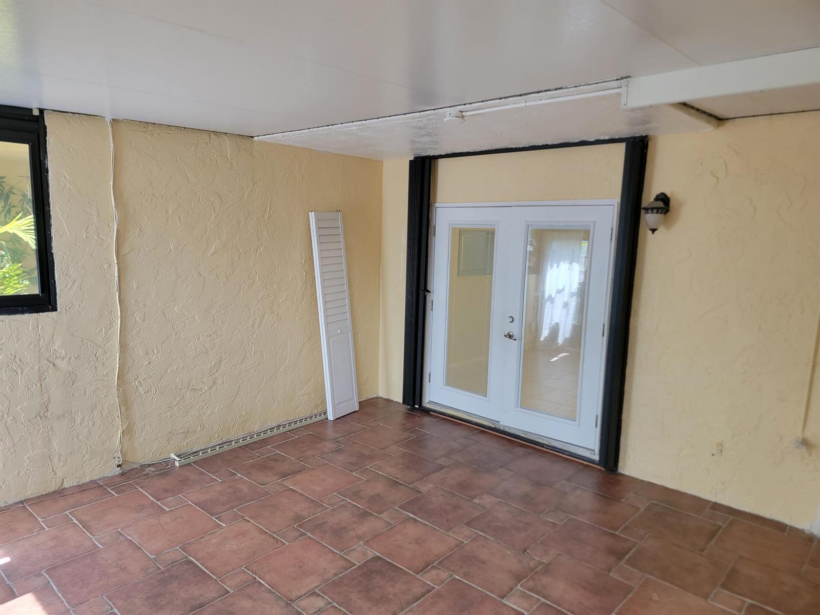 A red front door opens onto a tiled patio with a low stucco wall — 791 SE 1st Way # 74, Deerfield Beach FL 33441, DEERFIELD BEACH, FL