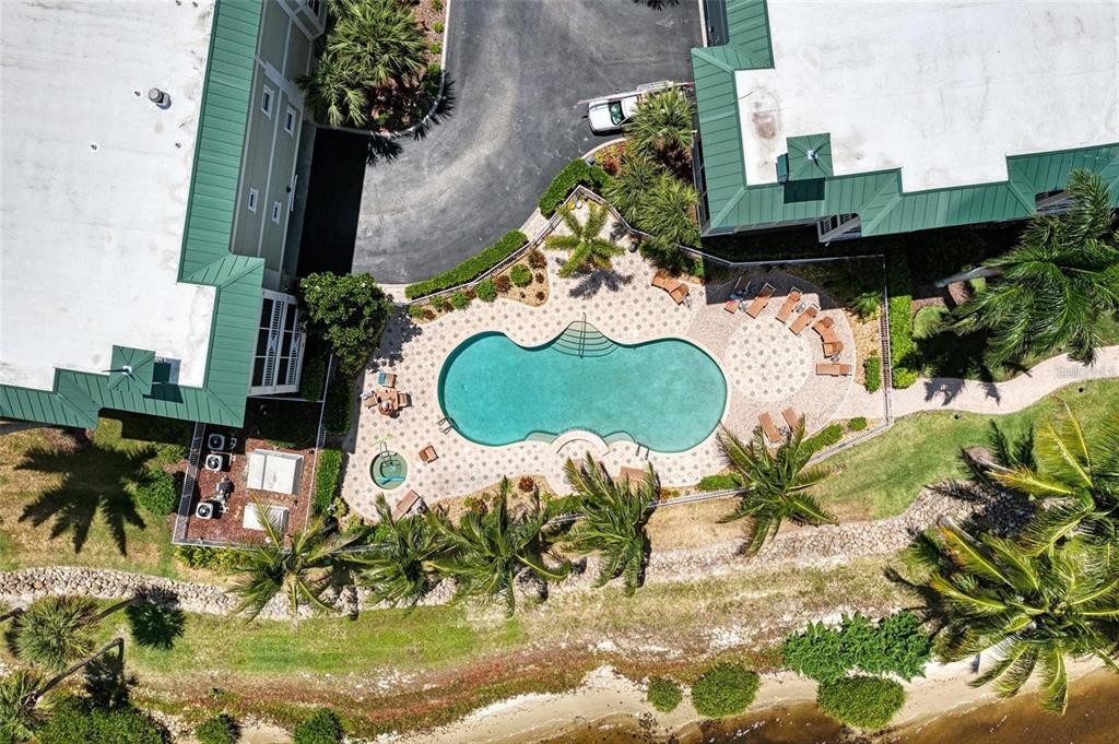 An aerial view shows a swimming pool and hot tub surrounded by a patio area — 5116 MELBOURNE STREET UNIT B-204, PORT CHARLOTTE, FL