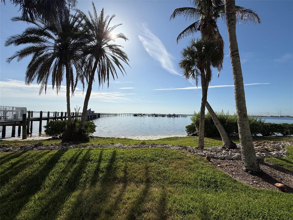 A grassy lawn with palm trees overlooks a calm bay with a long wooden pier — 5116 MELBOURNE STREET UNIT B-204, PORT CHARLOTTE, FL