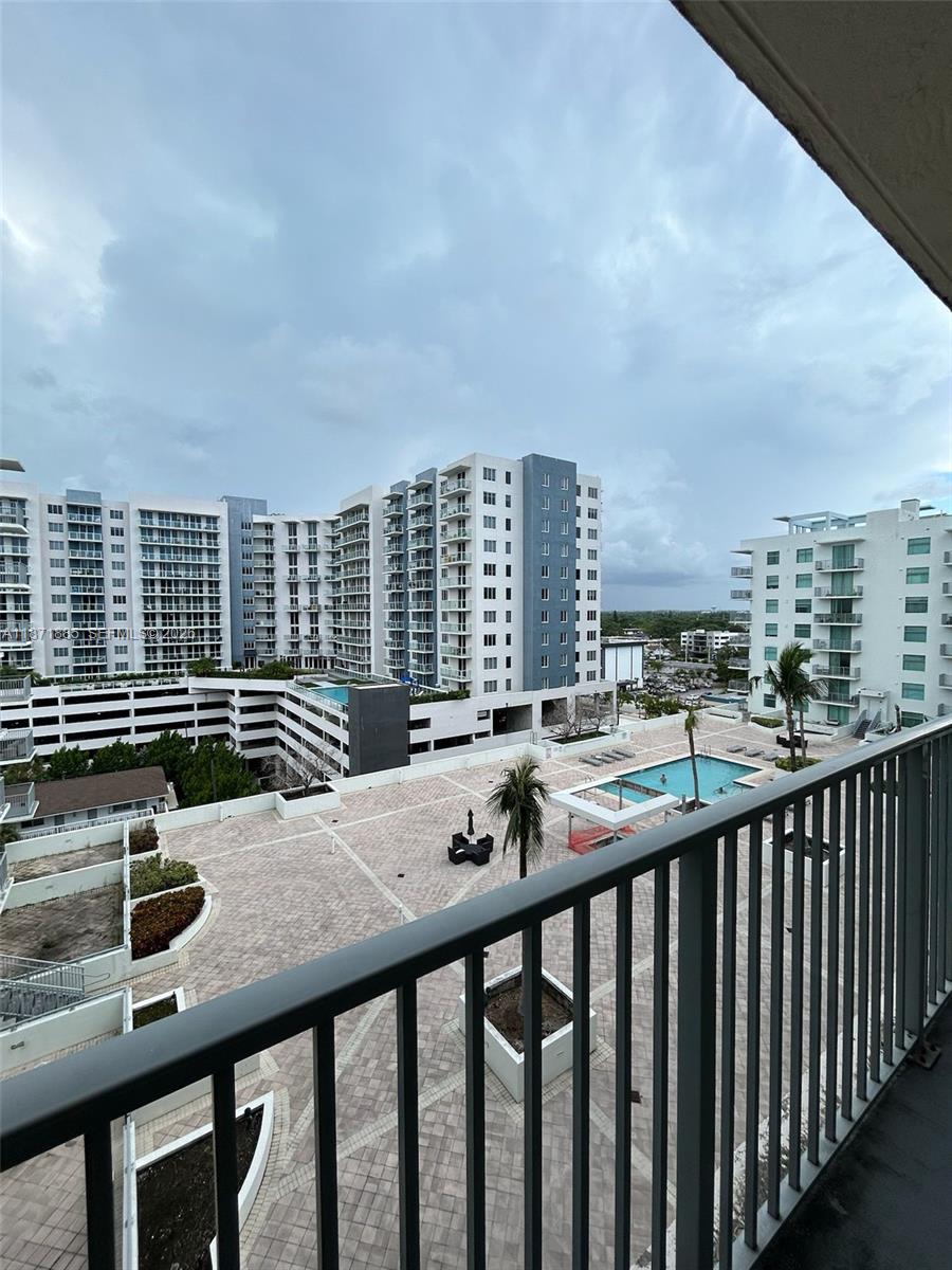 A balcony view overlooks a paved courtyard with a swimming pool and surrounding apartment buildings — 140 S Dixie Hwy # 816, Hollywood FL 33020, HOLLYWOOD, FL