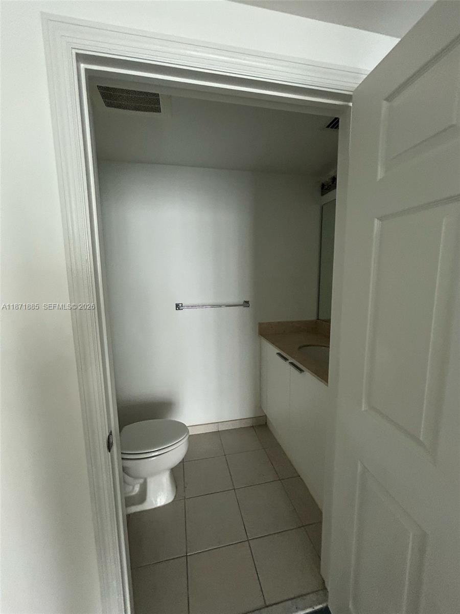 A small bathroom features a white toilet, a vanity with a sink, and tiled flooring — 140 S Dixie Hwy # 816, Hollywood FL 33020, HOLLYWOOD, FL