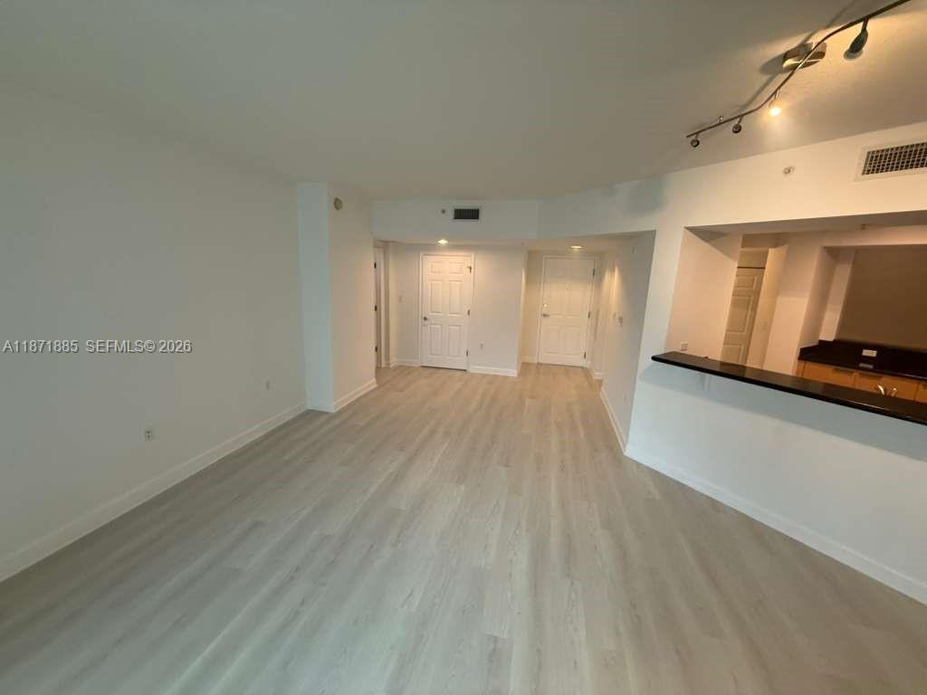 An interior view of a living area with light wood flooring and a kitchen pass-through — 140 S Dixie Hwy # 816, Hollywood FL 33020, HOLLYWOOD, FL