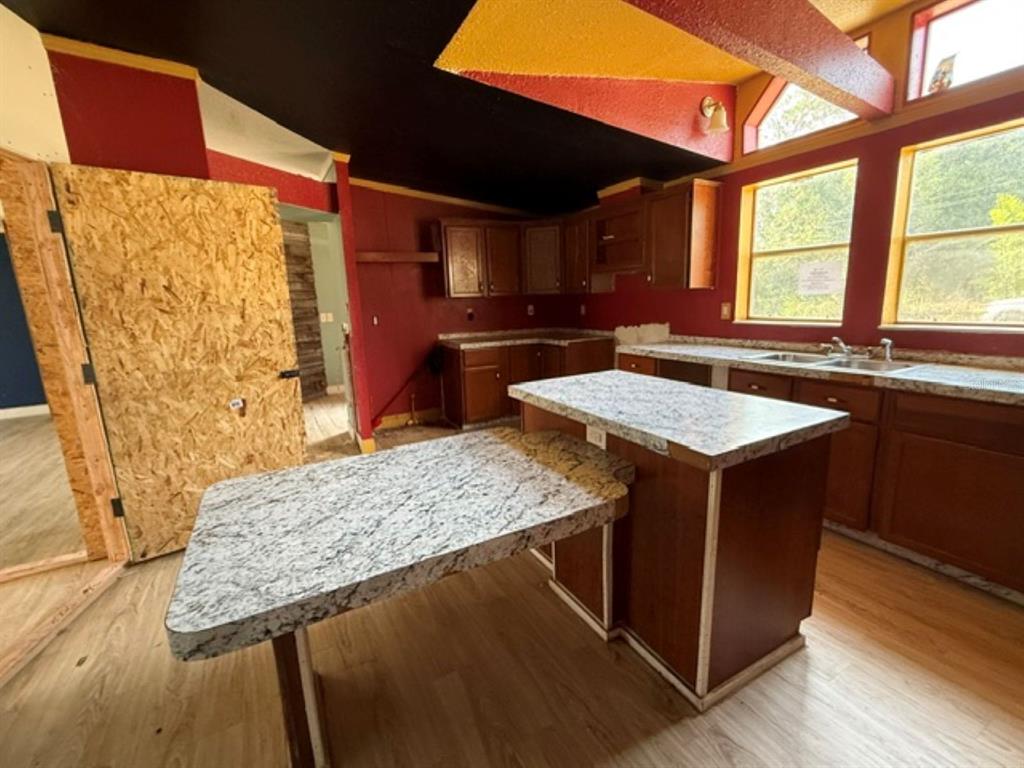 A kitchen features dark wood cabinets, granite-look countertops, red walls, and a black ceiling — 11881 RANCHO DRIVE, LEESBURG, FL