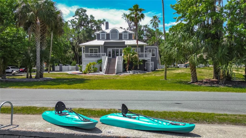 Two turquoise kayaks sit on a concrete ledge in front of a gray elevated house — 980 N GARDENVIEW TERRACE, CRYSTAL RIVER, FL