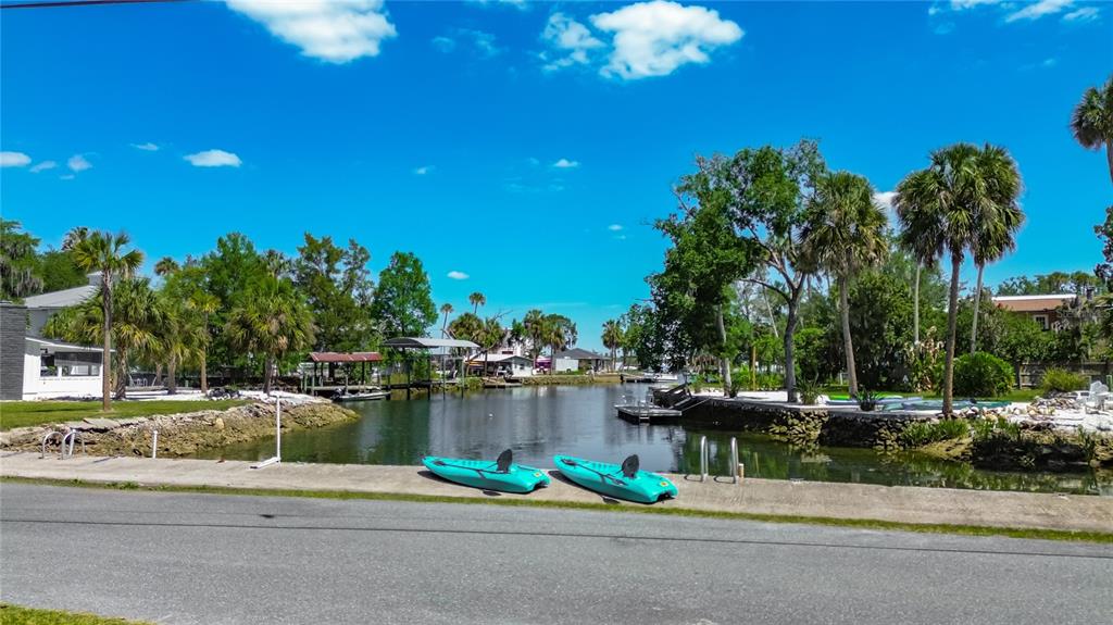 Two turquoise kayaks rest on a concrete bulkhead beside a canal lined with palm trees — 980 N GARDENVIEW TERRACE, CRYSTAL RIVER, FL