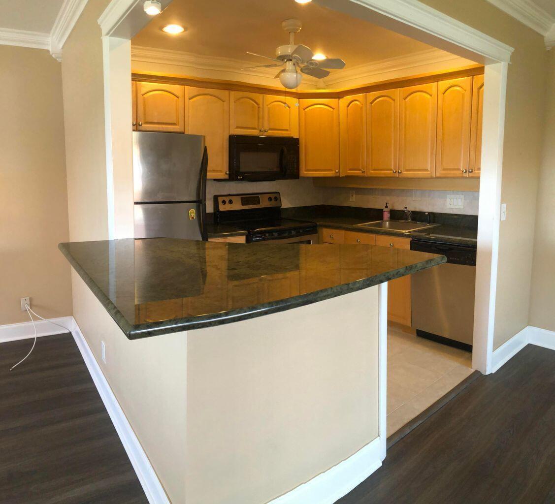 A kitchen with wood cabinets, stainless steel appliances, and a dark granite breakfast bar — 163 Waterford G, Delray Beach FL 33446, DELRAY BEACH, FL