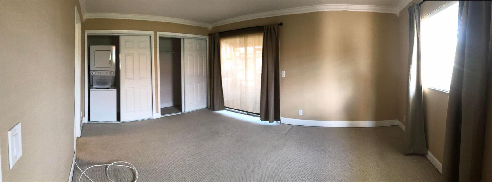 A bedroom with beige carpet, tan walls, a sliding glass door, and a laundry closet — 163 Waterford G, Delray Beach FL 33446, DELRAY BEACH, FL
