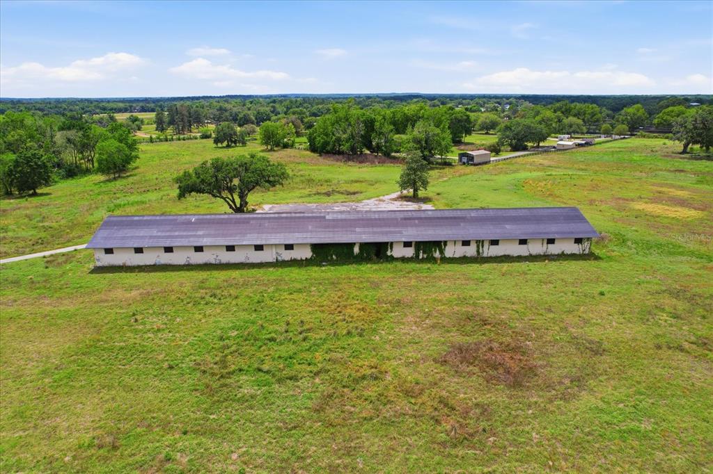 An aerial view shows a long, single-story white building with a dark roof in a field — 5465 NW 110TH AVENUE, OCALA, FL
