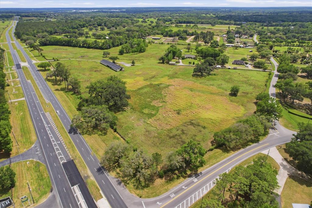 An aerial view shows a large, grassy vacant lot bordered by a highway and road — 5465 NW 110TH AVENUE, OCALA, FL