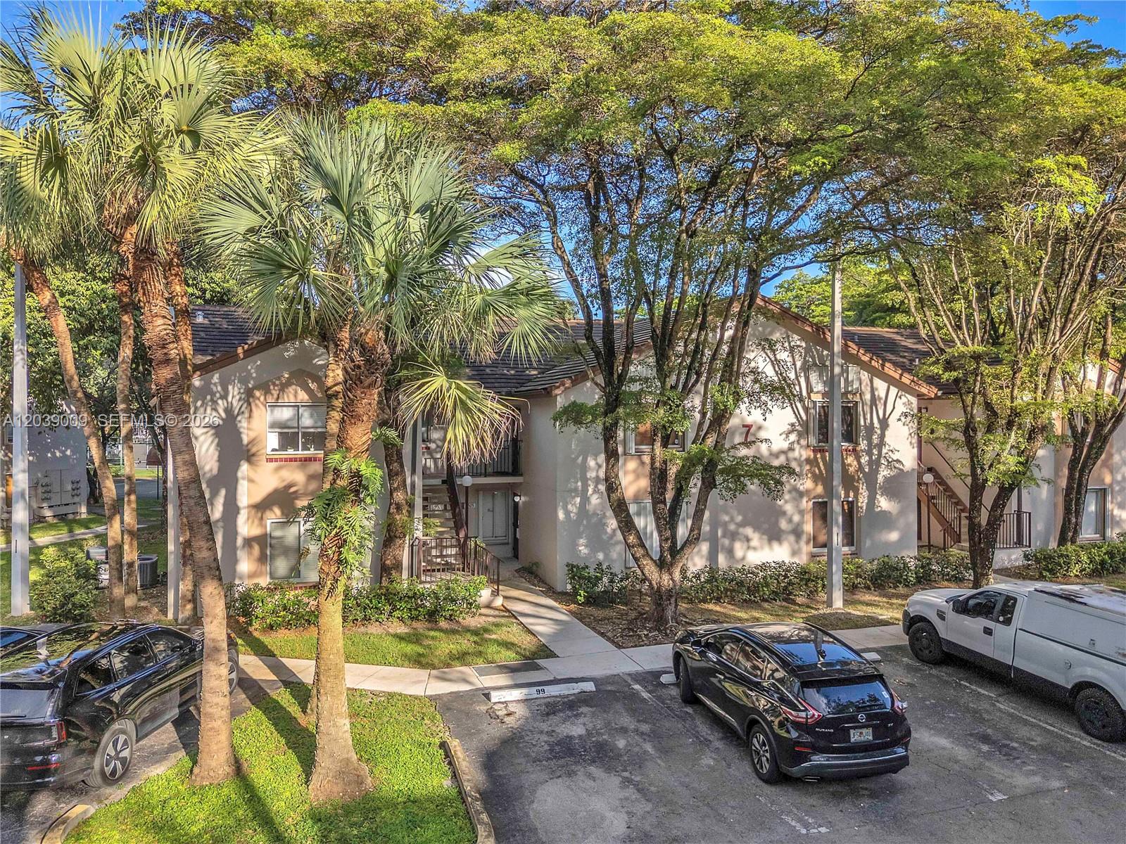 An exterior view of a two-story apartment building with palm trees and parked cars — 9507 SW 140th Ct # 9507, Miami FL 33186, MIAMI, FL