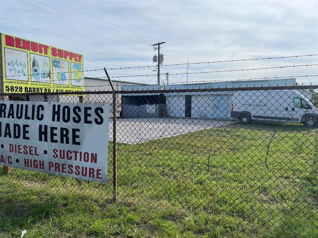 A chain-link fence stands in front of a commercial building with a supply sign — 7810 ANDERSON ROAD, TAMPA, FL