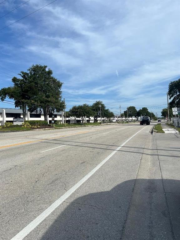 A view of a multi-lane road with a commercial building and trees in the background — 7810 ANDERSON ROAD, TAMPA, FL