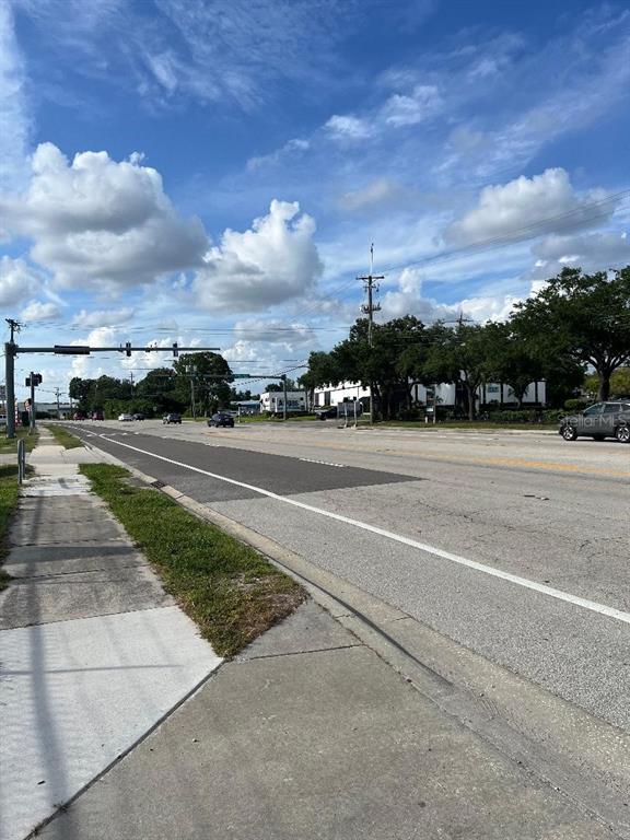A view of a multi-lane road intersection with a sidewalk and trees under a cloudy sky — 7810 ANDERSON ROAD, TAMPA, FL