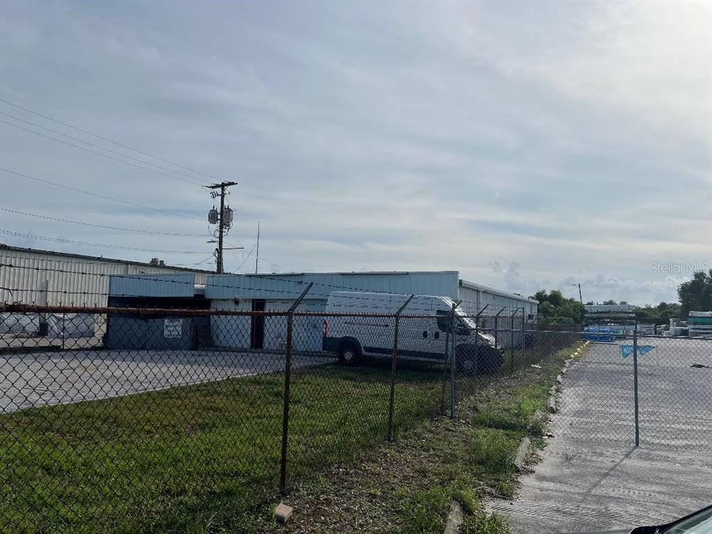 A white van is parked in front of a metal industrial building behind a chain-link fence — 7810 ANDERSON ROAD, TAMPA, FL