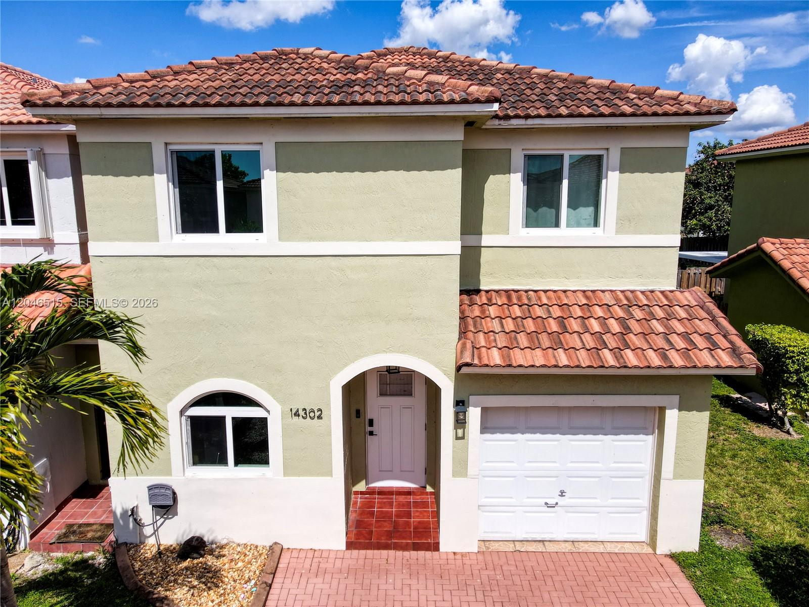 A two-story house with a light green stucco exterior, red tile roof, and white garage — 14302 SW 133rd Ct, Miami FL 33186, MIAMI, FL