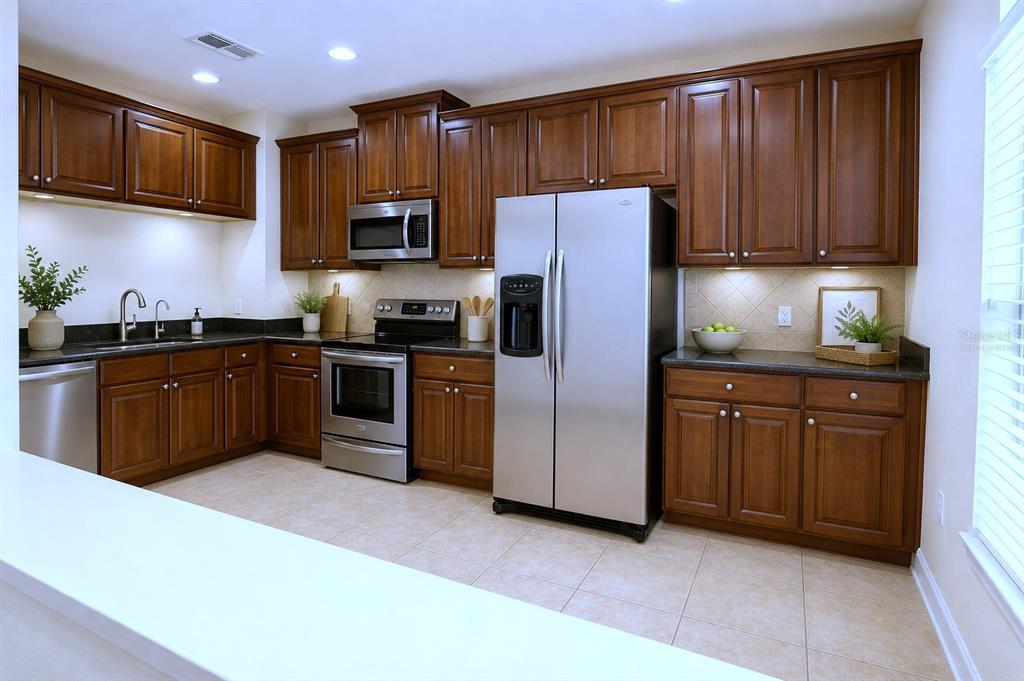 A kitchen features dark wood cabinets, stainless steel appliances, and granite countertops — 4624 MESSINA DRIVE, LAKE MARY, FL