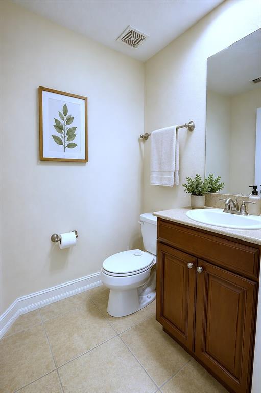 A bathroom features a wooden vanity, a white toilet, a framed leaf print, and tile flooring — 4624 MESSINA DRIVE, LAKE MARY, FL