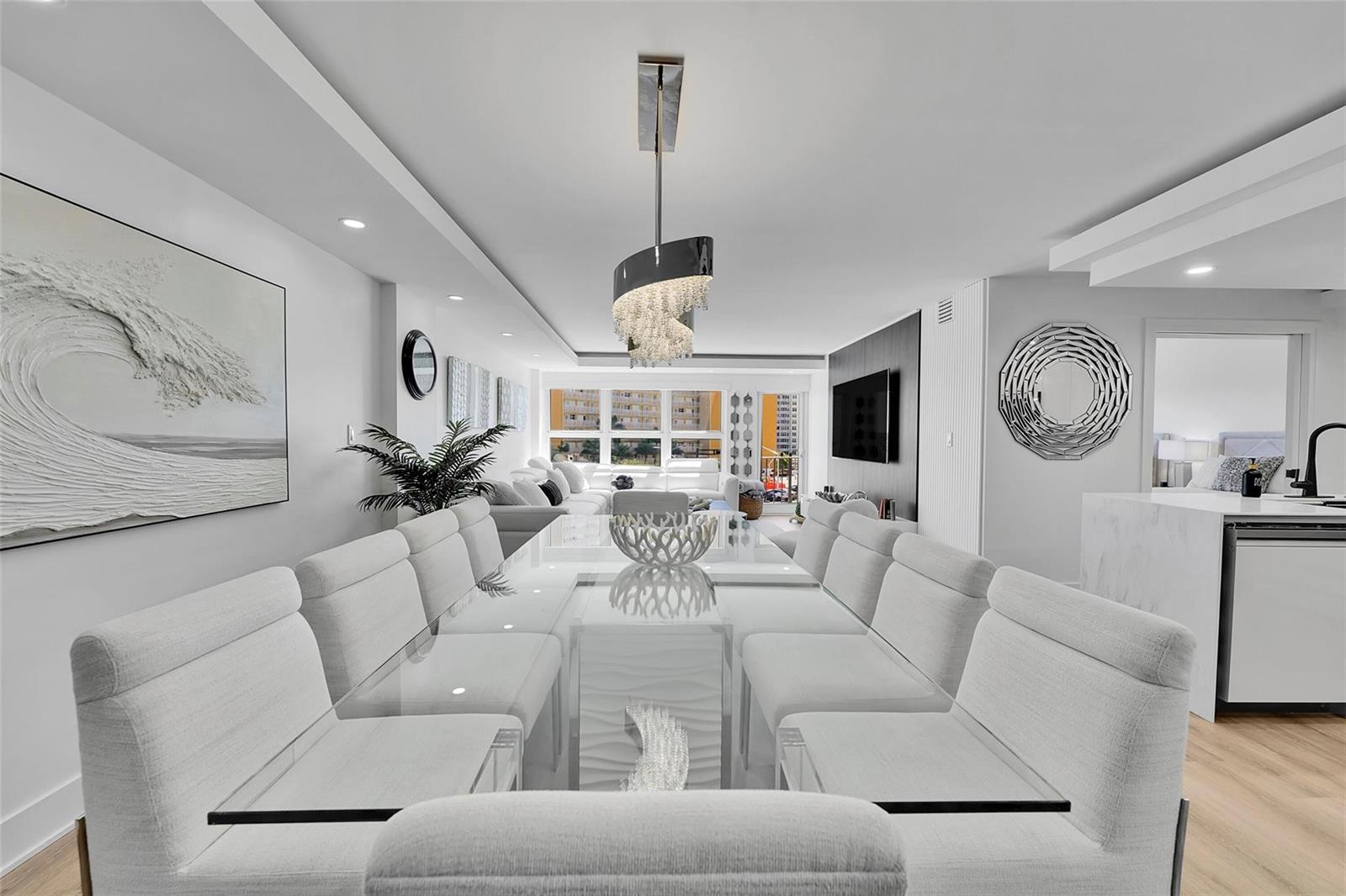 A modern dining room features a glass table, white upholstered chairs, and a crystal chandelier — 405 N Ocean Boulevard # 306, Pompano Beach FL 33062, POMPANO BEACH, FL