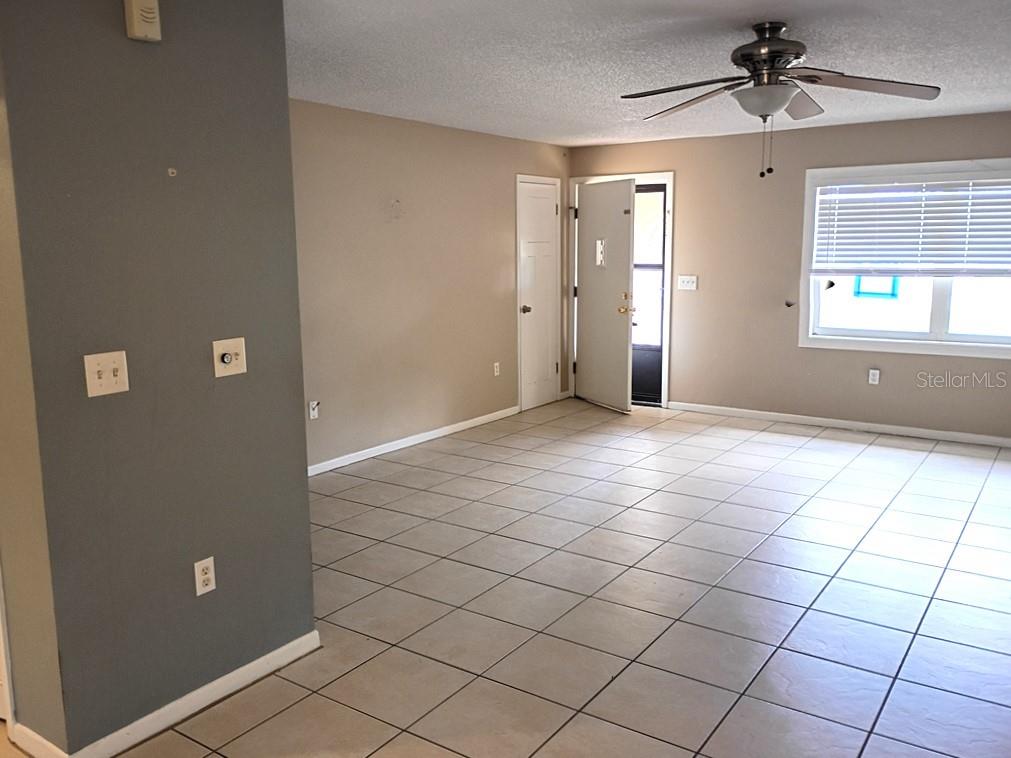 An interior view of a room with light-colored tile flooring, beige walls, and a ceiling fan — 1208 S CANAL BOULEVARD, SEBRING, FL
