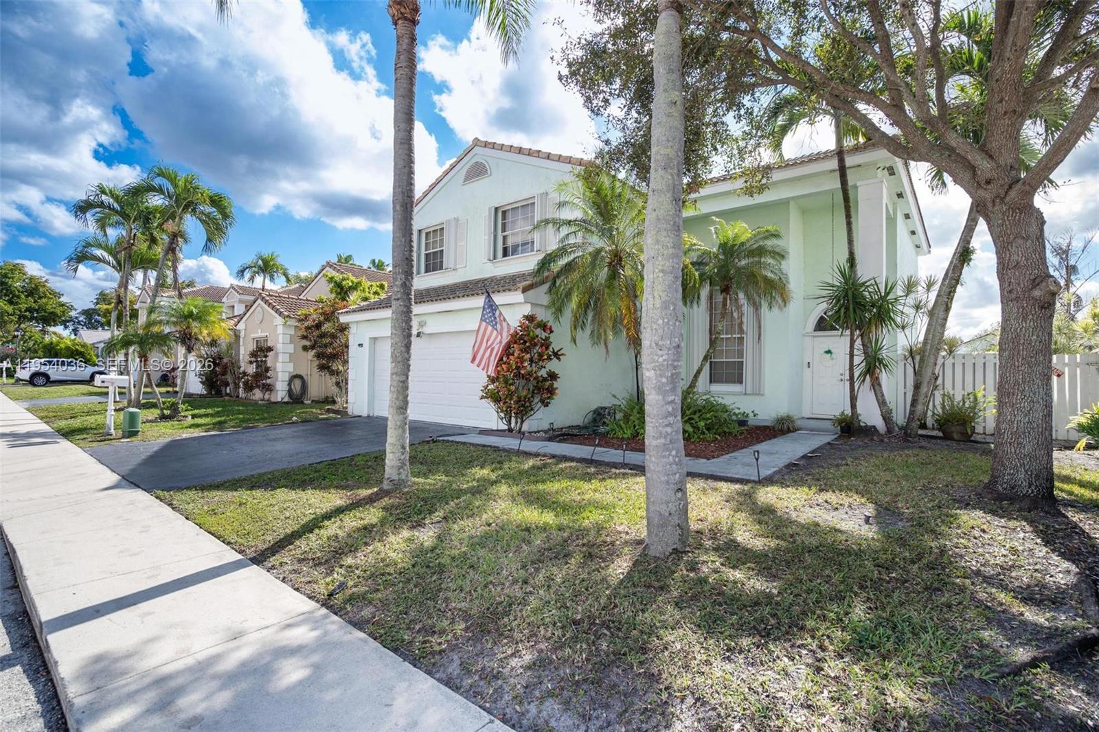 A two-story, light green suburban house with a two-car garage and palm trees — 13930 Oak Ridge Dr, Davie FL 33325, DAVIE, FL