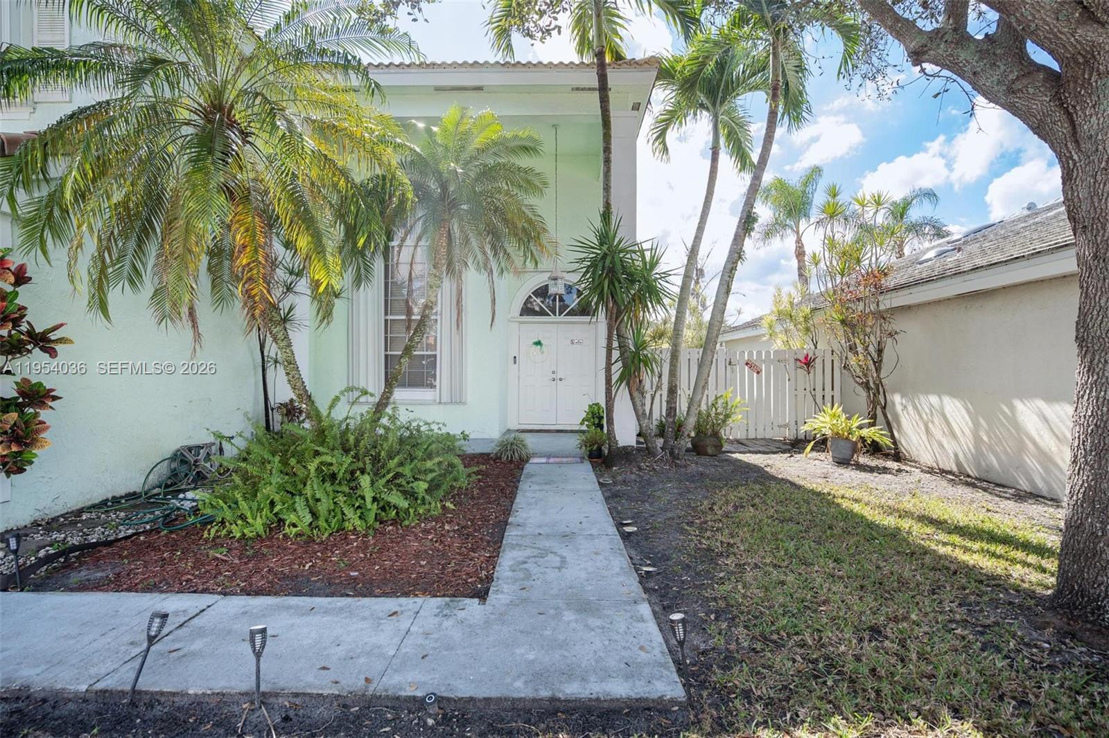 A light green house exterior features a white double door entrance and palm trees — 13930 Oak Ridge Dr, Davie FL 33325, DAVIE, FL