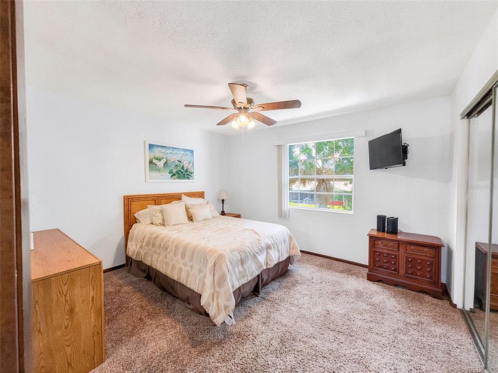 A bedroom features a bed, a wooden dresser, a ceiling fan, and a window — 175 YORKTOWNE DRIVE UNIT UT11, DAYTONA BEACH, FL