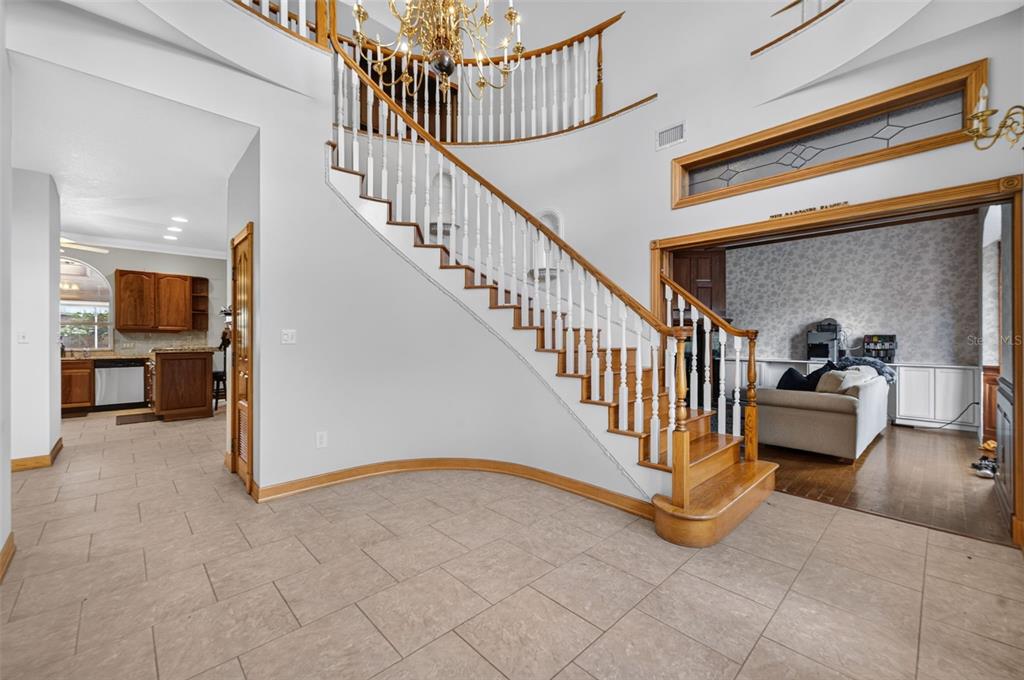 A foyer features a curved staircase with white railings and tile flooring, leading to adjacent rooms — 4657 HICKORY TREE ROAD, ST CLOUD, FL