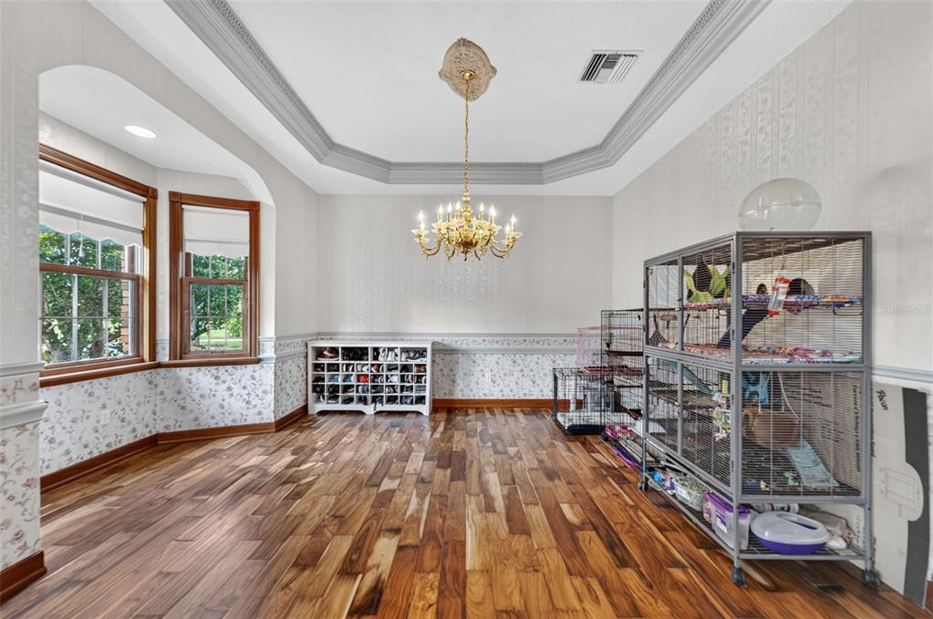 A dining room with hardwood floors, a chandelier, a shoe rack, and large animal cages — 4657 HICKORY TREE ROAD, ST CLOUD, FL