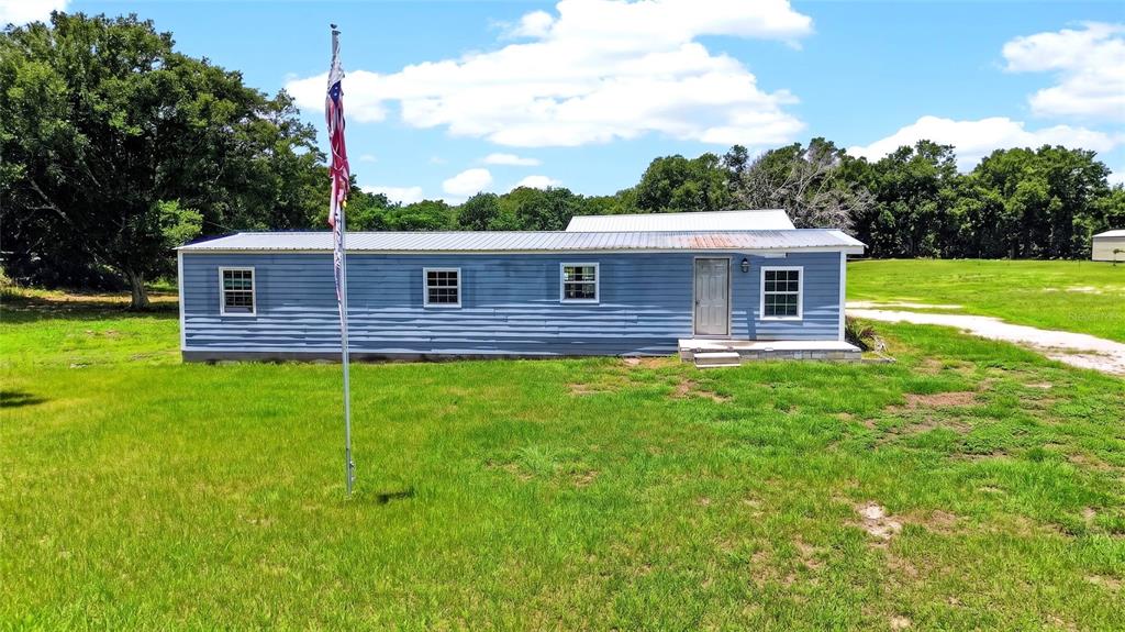 A blue, single-story manufactured home sits on a grassy lot with a flagpole — 4162 LAUGHLIN ROAD, MOUNT DORA, FL