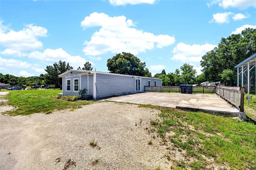A light blue mobile home with a concrete patio and a wooden fence — 4162 LAUGHLIN ROAD, MOUNT DORA, FL