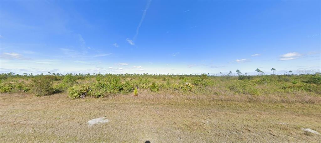A wide, flat, undeveloped grassy lot under a clear blue sky — 306 CALENDULA DRIVE, INDIAN LAKE ESTATES, FL