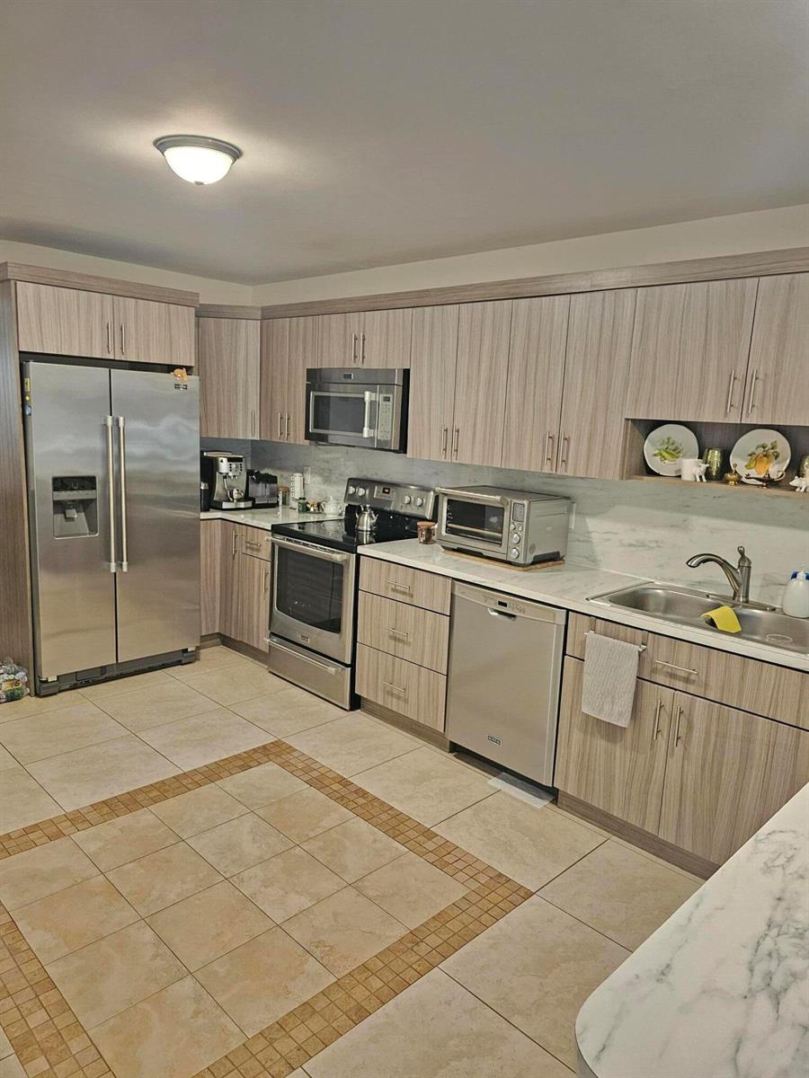 A kitchen features light wood-grain cabinets, stainless steel appliances, and a marble-look countertop — 1412 SW 110th Way, Davie FL 33324, DAVIE, FL