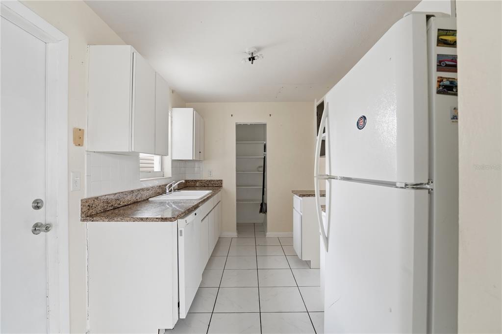 A kitchen with white cabinets, granite countertops, a white refrigerator, and white tile flooring — 21123 GLENDALE AVENUE, PORT CHARLOTTE, FL