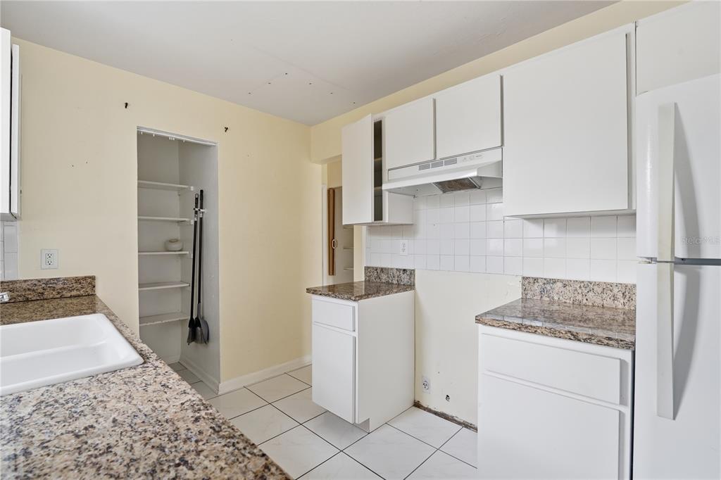 A kitchen features white cabinets, granite countertops, a white tiled backsplash, and an open pantry — 21123 GLENDALE AVENUE, PORT CHARLOTTE, FL