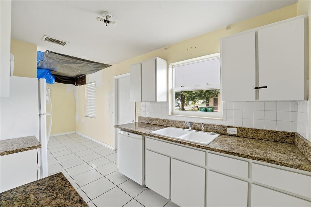 A kitchen with white cabinets, granite countertops, tile flooring, and an unfinished ceiling area — 21123 GLENDALE AVENUE, PORT CHARLOTTE, FL