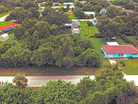 An aerial view shows a residential lot with dense trees and nearby houses — 21511 CARLETON AVENUE, PORT CHARLOTTE, FL