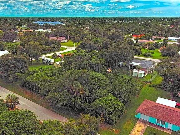 An aerial view shows a wooded residential lot with a small structure and nearby houses — 21511 CARLETON AVENUE, PORT CHARLOTTE, FL