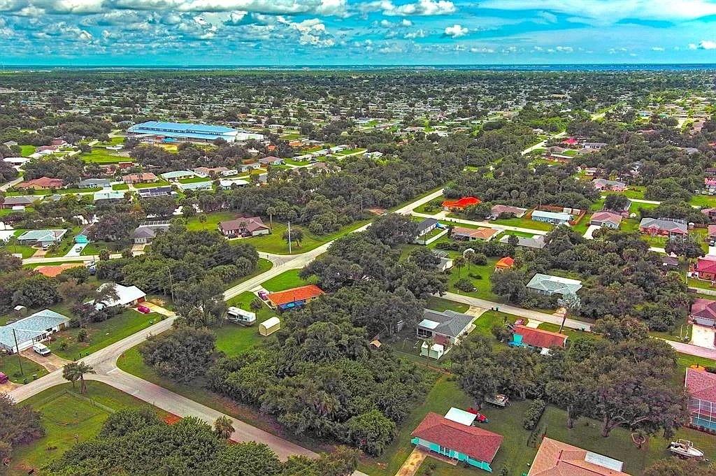 An aerial view of a suburban neighborhood with houses, trees, and roads under a cloudy sky — 21511 CARLETON AVENUE, PORT CHARLOTTE, FL