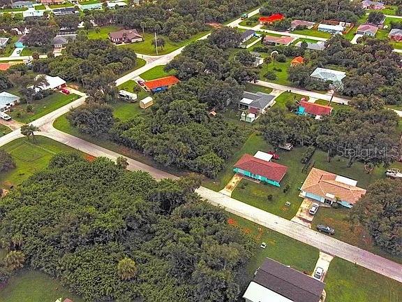 An aerial view shows a residential neighborhood with houses, streets, and dense tree cover — 21511 CARLETON AVENUE, PORT CHARLOTTE, FL