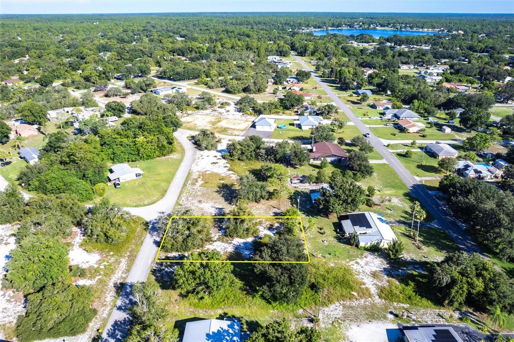 An aerial view shows a vacant, wooded residential lot outlined in yellow within a suburban neighborhood — 913 HOLLYHOCK COURT, LAKE PLACID, FL