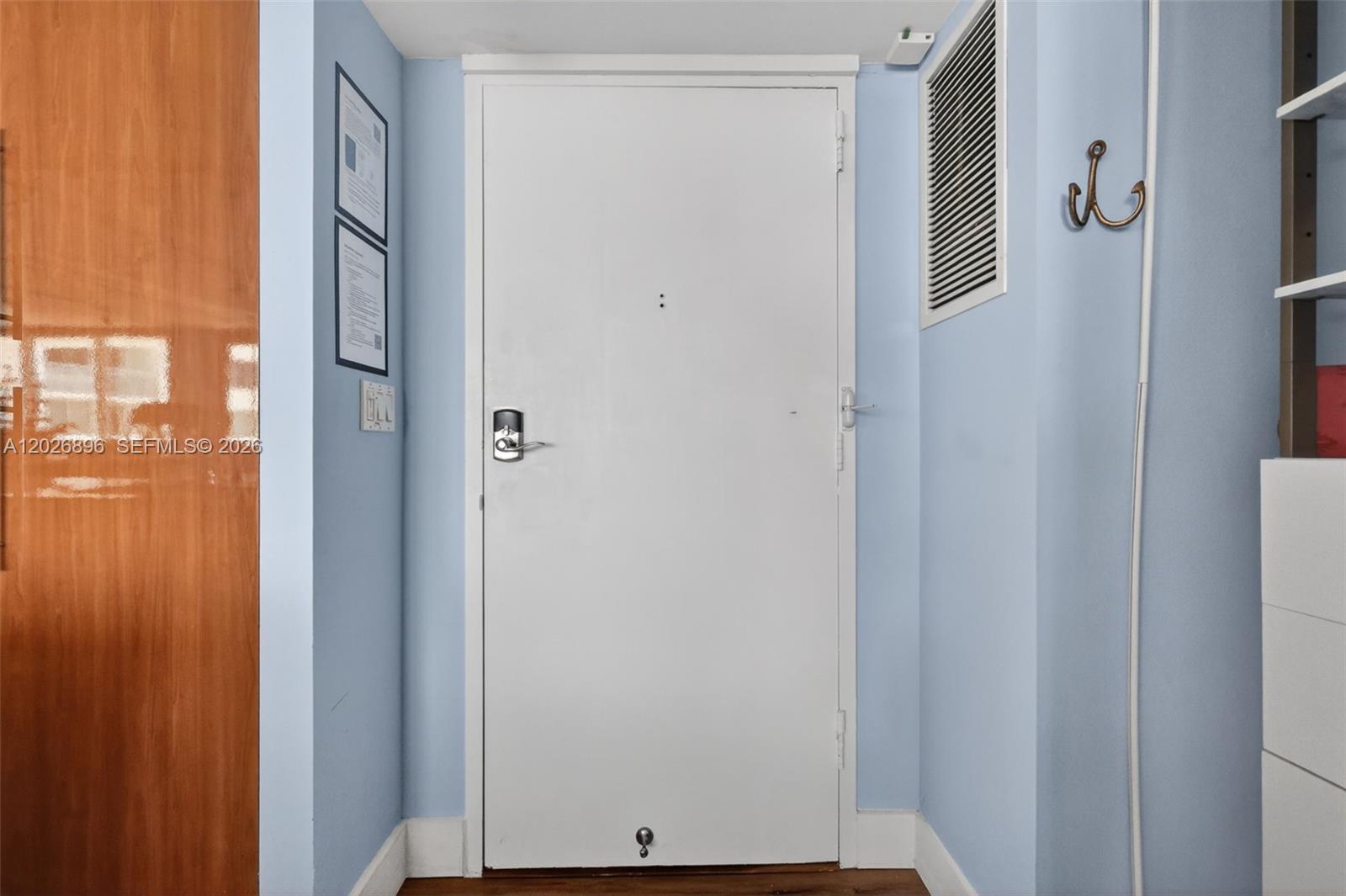 A white entry door with a digital lock is centered in a light blue hallway — 7135 Collins Ave # 1124, Miami Beach FL 33141, MIAMI BEACH, FL