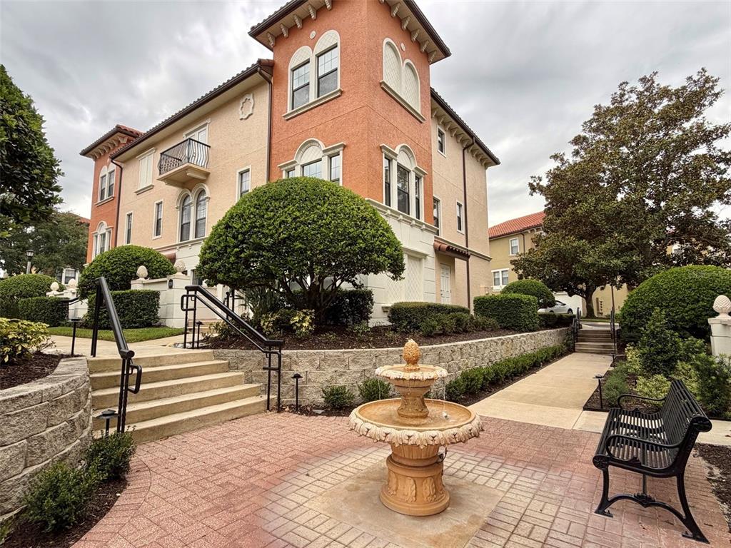 A multi-story stucco building with a fountain and bench in the foreground — 3728 MESSINA DRIVE, LAKE MARY, FL