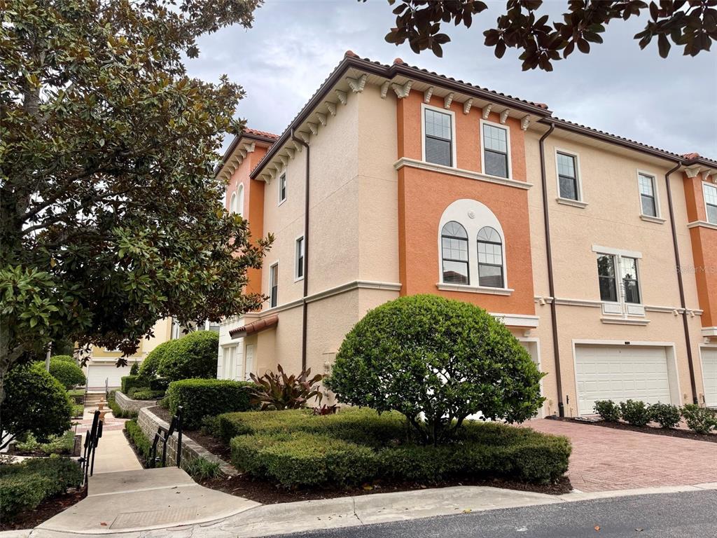 A multi-story townhouse with stucco walls, arched windows, and a paved driveway — 3728 MESSINA DRIVE, LAKE MARY, FL