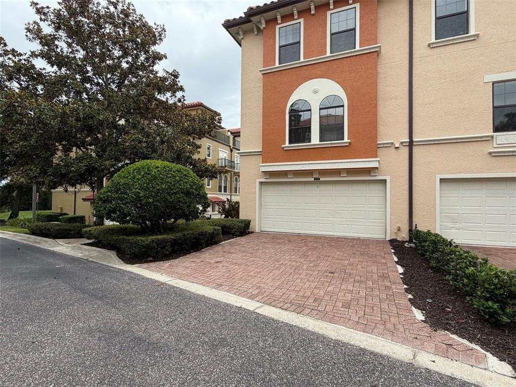 An exterior view of a multi-story townhouse with a brick paver driveway and garage — 3728 MESSINA DRIVE, LAKE MARY, FL