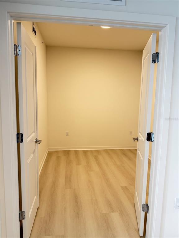 An open-concept living area features light wood-look flooring and a kitchen with dark cabinetry — 5587 MILLENIA BOULEVARD UNIT 202, ORLANDO, FL