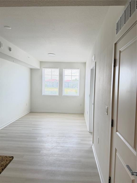 A small, empty room with light wood-look flooring and double doors — 5587 MILLENIA BOULEVARD UNIT 202, ORLANDO, FL