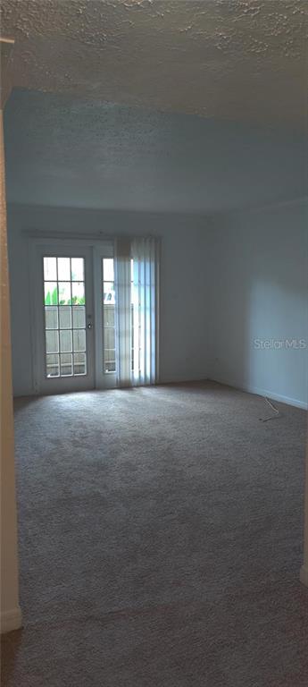 An empty room with beige carpet, white walls, and glass French doors leading outside — 315 WYMORE ROAD UNIT 104, ALTAMONTE SPRINGS, FL
